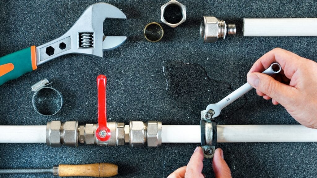 Plumber repairing a pipe valve with an adjustable wrench in Estero