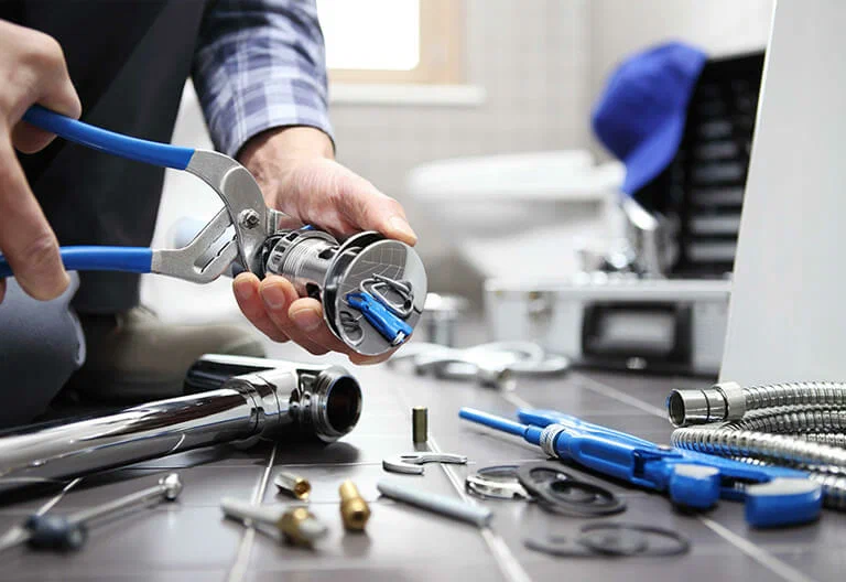 Technician repairing a plumbing fixture with professional tools in Estero