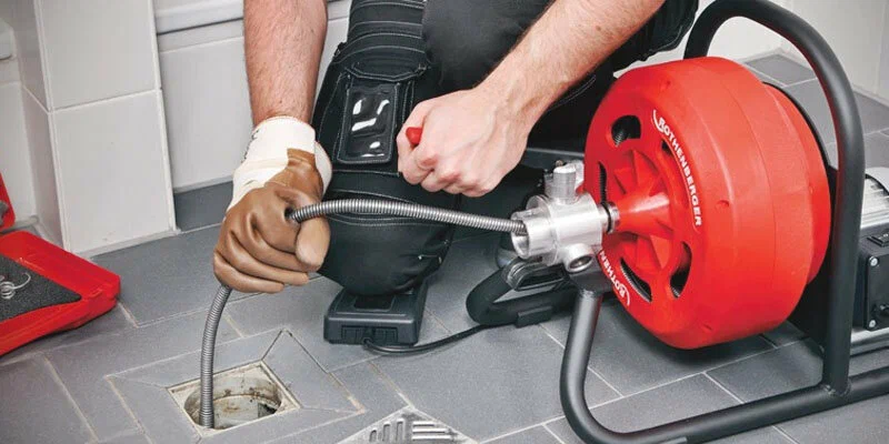 Plumber using a drain-cleaning machine in Estero
