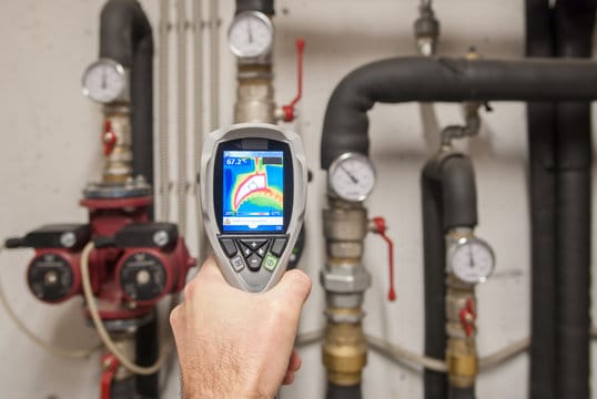 Plumber using a thermal imaging camera to inspect pipes in Estero