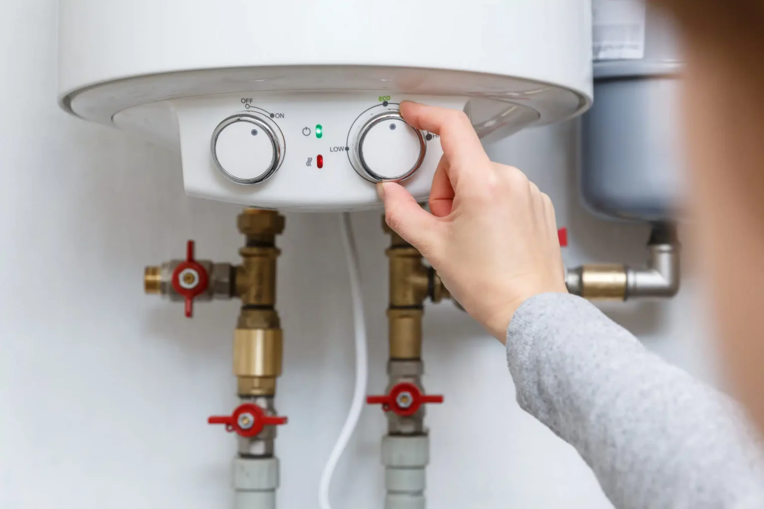 Homeowner adjusting the temperature controls on a water heater in Estero